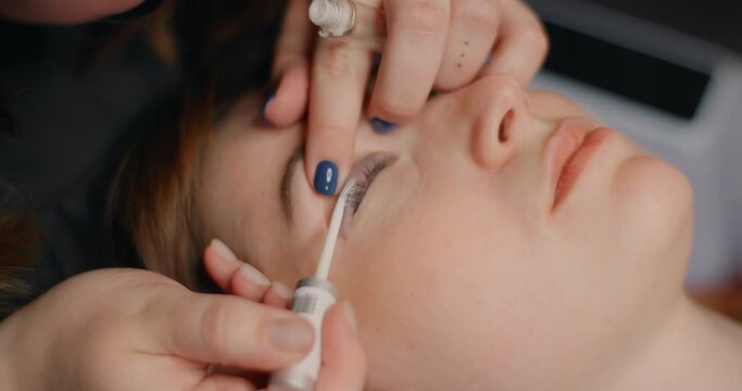Lashmaker does the eyelash lamination procedure for the client in the beauty salon, cosmetic services, beauty care procedures, 4k 60p Prores HQ