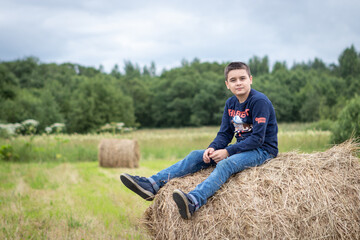Naklejka na ściany i meble boy sitting on a haystack