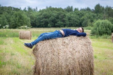 Naklejka na ściany i meble the boy lies on the hay in the field