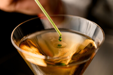 beautiful close-up of glass with drink in which adds drop of ingredient from dropper