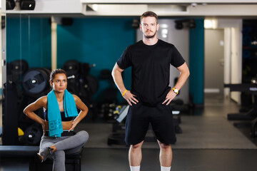 Fitness instructor with a female client. Lovely couple posing in a fitness club.
