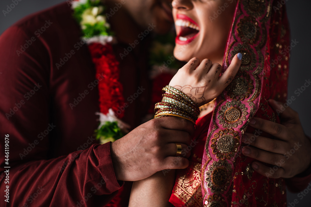 Wall mural partial view of blurred indian man in turban holding hand of happy bride in traditional headscarf is