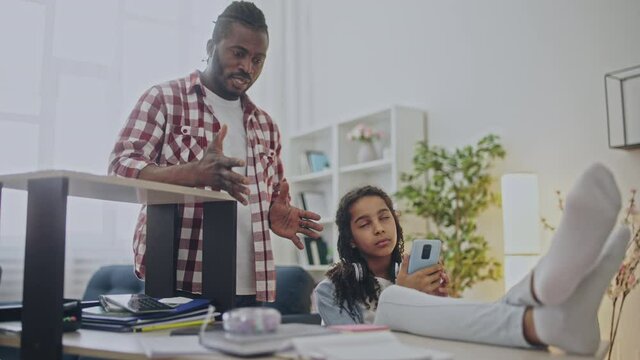 Black father dissatisfied with teen daughter using phone, ignoring her parent