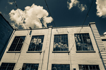 large industrial building with clouds and sky reflecting from windows 
