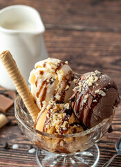 Chocolate, cream and caramel Roma ice cream in a glass bowl with hazelnut and chocolate sauce poured over it.