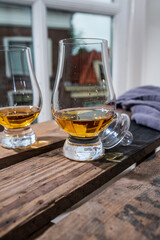Dram of single malt scotch whisky served in tasting glass with view on old window and houses