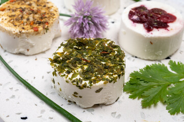 Cheese collection, variety of fresh white soft goat French cheeses with aromatic herbs, berries and green pesto