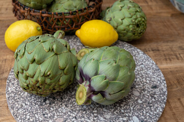Obraz premium Fresh ripe green artichokes heads with yellow lemons ready to cook