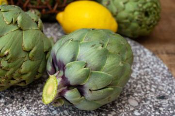 Obraz premium Fresh ripe green artichokes heads with yellow lemons ready to cook