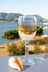 Summer on French Riviera, drinking of cold white or gris rose wine from Cotes de Provence on outdoor terrase with view on harbour of Toulon, Var, France and sea shells