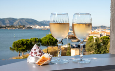 Summer on French Riviera, drinking of cold white or gris rose wine from Cotes de Provence on outdoor terrase with view on harbour of Toulon, Var, France and sea shells