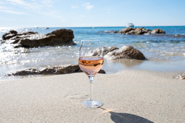 Summer time in Provence, glass of cold rose wine on sandy beach and blue sea near Saint-Tropez, Var department, France