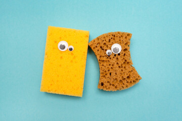 Two cleaning sponges with googly eyes. A funny face. Round eyes. Blue background. Holiday.