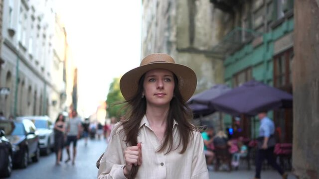 Beautiful girl in a hat walking through the old town. Portrait