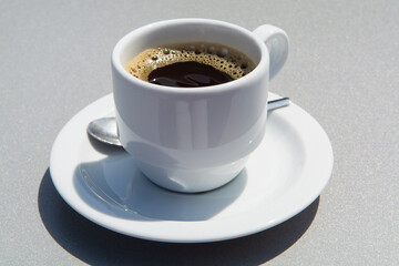 White cup of black coffie on gray background