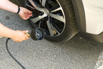 driver checking pressure and inflate a wheel of a car on gasoline station