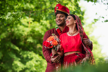 cheerful indian man in turban hugging bride in red sari