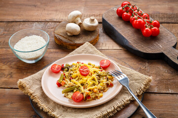 Risotto with beefs and cheese in a plate on a wooden background on a napkin next to rice mushrooms and tomatoes on planks.