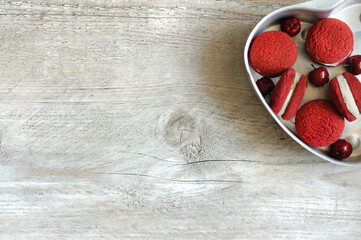 Red with cream white biscuits in metal shape with copy space and gray wood background. Selective focus
