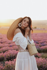 beautiful woman with dark hair in elegant white dress posing in bloomig lavender field on sunset
