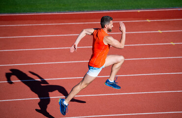 energetic athletic muscular man runner running on racetrack at outdoor stadium, marathon