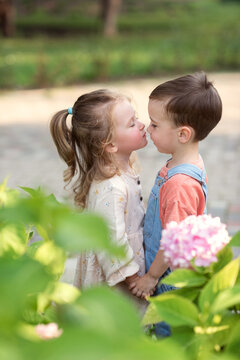 little boy and girl stand holding hands and kiss. Valentine's Day