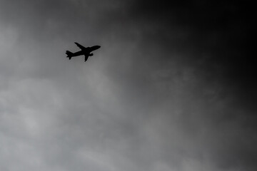 Plane flying into storm. Silhouette aircraft flies in thunderclouds. Air crash hazard concept. Passenger airliner on a background of a hurricane