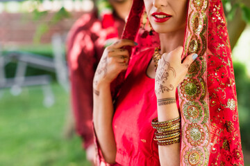 cropped view of indian bride in sari and headscarf near blurred man on background