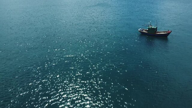 Aerial view. Beautiful shot of the colorful fishing boat going to the port.  Turquoise water of the sea in a paradise of a tropical island the stunning nature somewhere in southeast Asia.