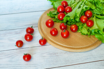 Naklejka na ściany i meble fresh cherry tomatoes and lettuce salad lie on the chopping board. High quality photo