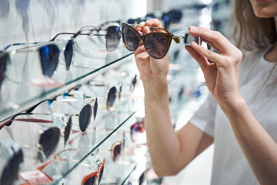 Young woman choosing sunglasses in optical store