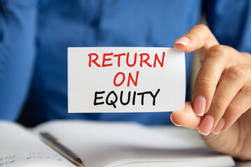 return on equity written on a paper card in woman hand