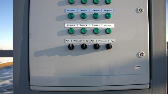 Colorful buttons with signs on control cabinet near basins at waste water treatment station on sunny winter day closeup