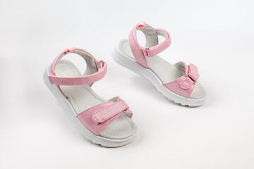 Pink children's sandals made of shiny leather with Velcro fasteners, flat white soles, isolated on a white background. A pair of fashionable children's sandals for a comfortable walk. 