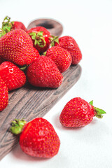 Elegant tender strawberry background. Ripe summer red berries. Sweet berry for morning breakfast, or berries for dessert. Whole strawberries on wooden board and white background