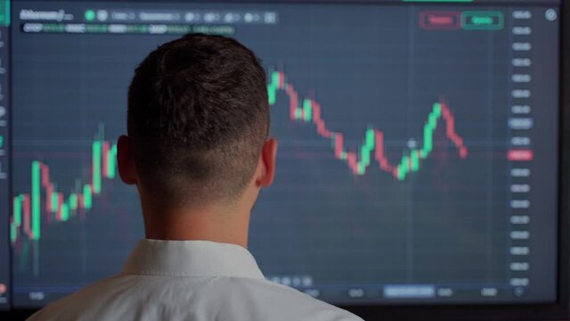 Man trader looking at graph currency money at screen indoors. Male businessman person check status online bank money finance. He dressed white shirt. Quotes eth and btc at stock exchange market chart