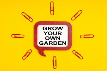 On a yellow background, paper clips and a mental plaque with the inscription - Grow Your Own Garden