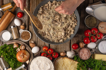 Pizza filling. In a skillet, the cook is stirring the pieces of mushrooms with a wooden spatula....