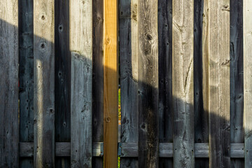 Diagonal play of light and shadow on an old weathered wooden fence supported by a relatively new batten.