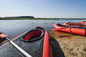 Red packraft rubber boats on the sand river bank. Selective focus. Active lifestyle concept.