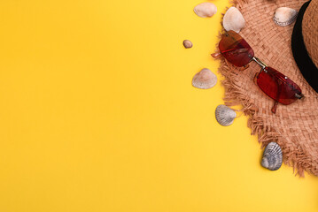 flat lay accessories for a summer holiday at a resort on the sea. anti-sun goggles, seashells, a straw hat. on a yellow background.. Top view, copy space