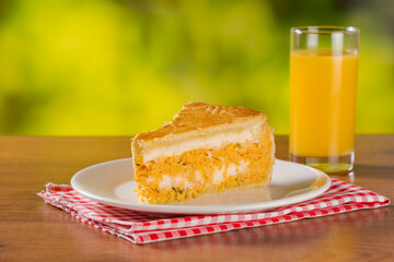 Slice of chicken pie with cheese on natural background, white plate and orange juice.