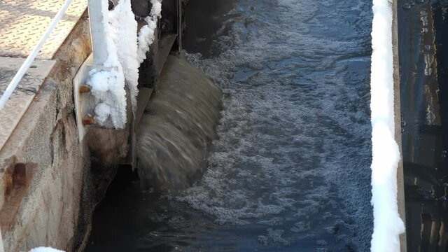 Pouring dirty water into pool to process at contemporary filtration station at sunset time in winter close view