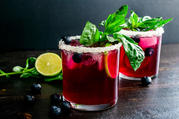 Roasted Blueberry Basil Margaritas Garnished with Fresh Basil and Blueberries: Margarita cocktails made with tequila, basil, and blueberries and rimmed with a salt and sugar mixture