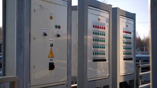 Control panels on empty metal bridge over basin with purifying wastewater at treatment station at sunset in winter