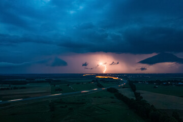 Obraz premium Heavy storm over express road and fields, dark clouds and lightning in the evening