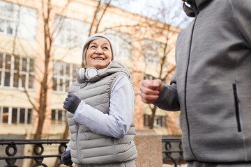 Obraz na płótnie Canvas Low angle portrait of active senior couple running outdoors in winter and smiling happily, copy space