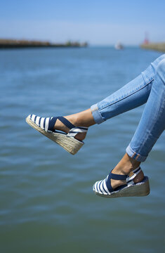 Girl legs wearing summer shoes with summer blue background. Espadrillas with a marine style
