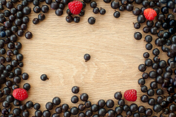 Fresh organic berries, black currant and raspberry, on wooden table. Raw food and healthy eating, berry diet. Ingredients for smoothies. Frame, copy space for inscription