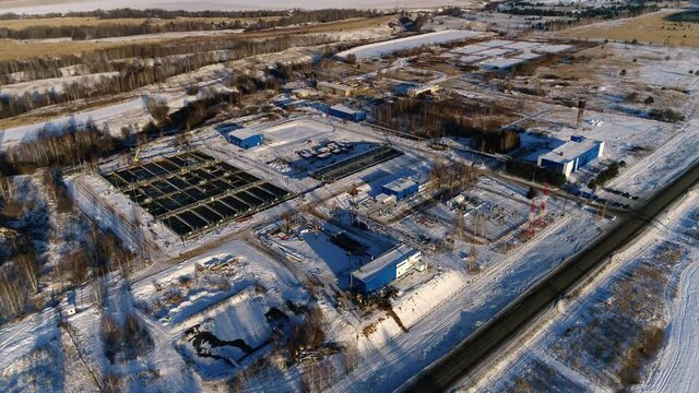 Wastewater treatment plant with processing reservoirs electrical distribution substation at sunset in winter aerial view